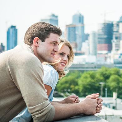 Man and woman leaning on edge of building