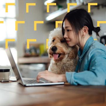 一个女人带着她的狗看着桌子上的笔记本电脑