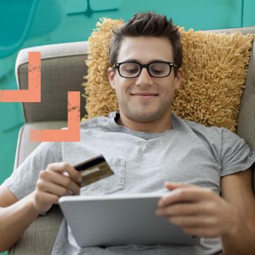 一个拿着信用卡和平板电脑坐在沙发上的男人