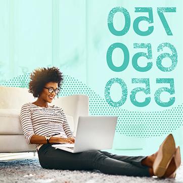 Woman looking at laptop while sitting on floor and leaning on a couch